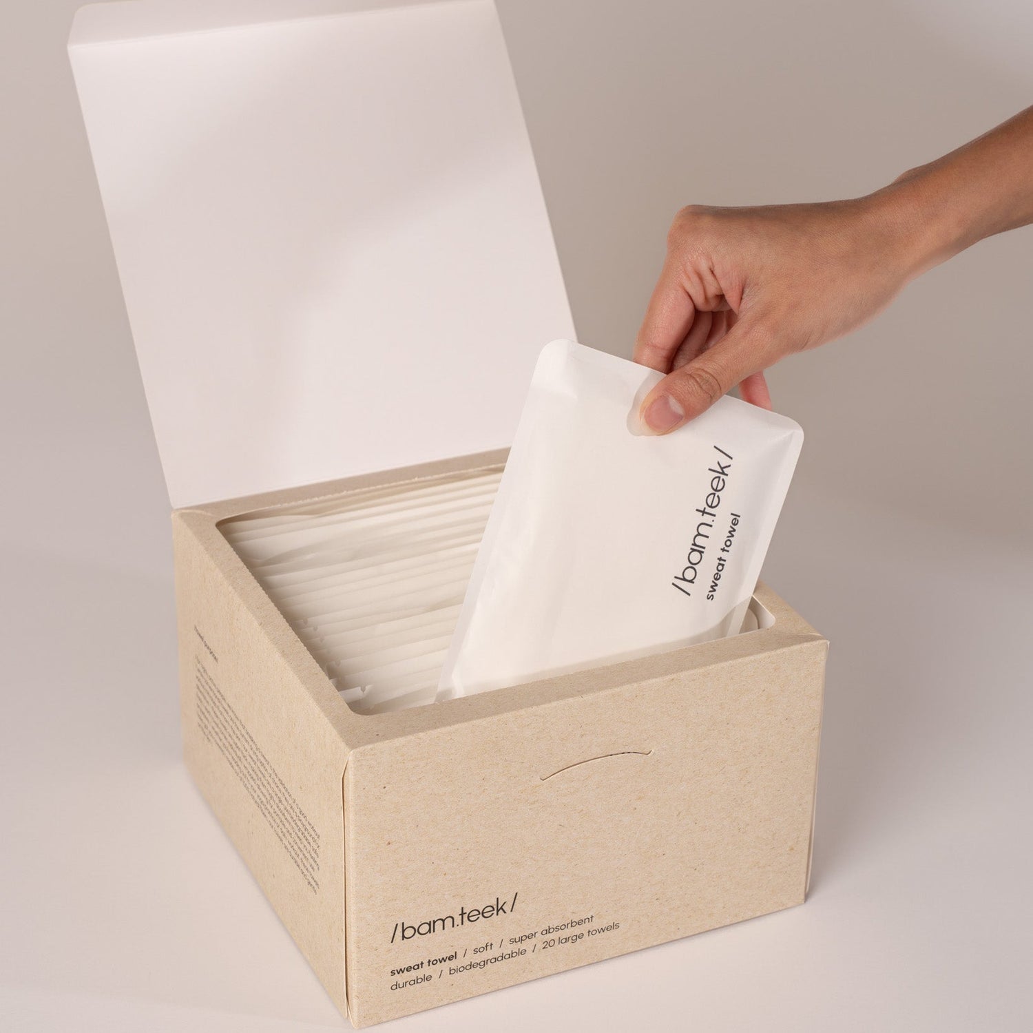 Hands holding a white, textured single-use towel from the Sweat Bundle for active skincare.